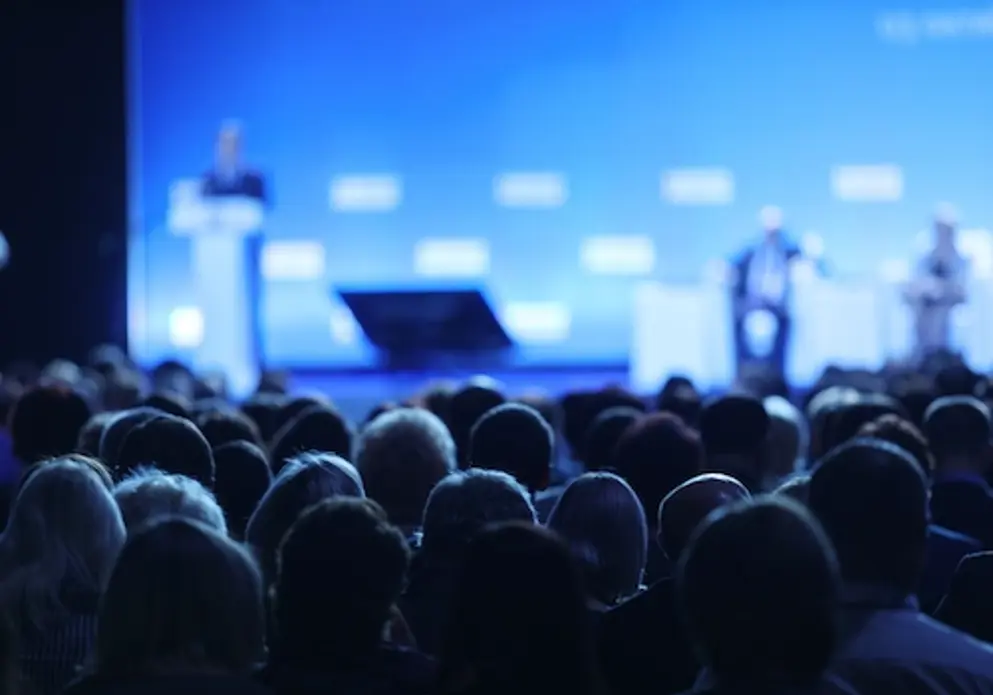 An audience listening to a speaker at a podium.