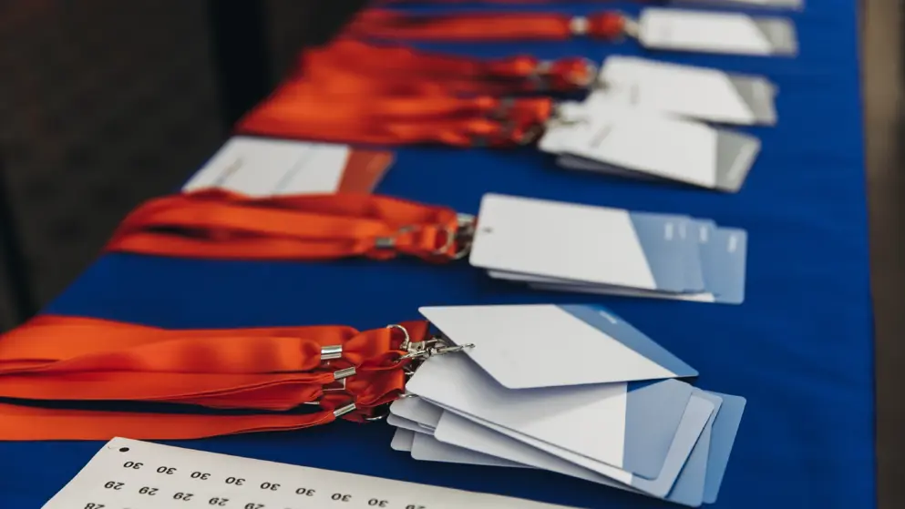 Process of checking in to congress event, registration desk table, visitors and attendees receiving lanyard with name badge and entry wristband bracelet and register electronic ticket